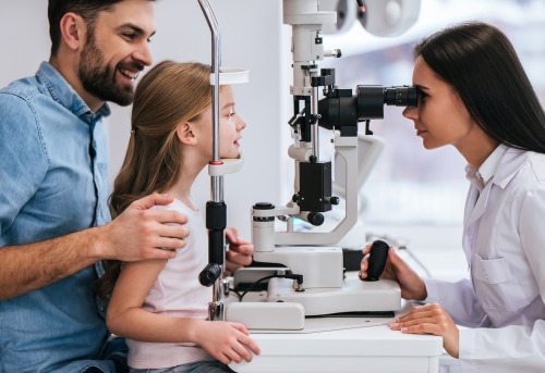 Father and his daughter are checking the eye vision in ophthalmology clinic.