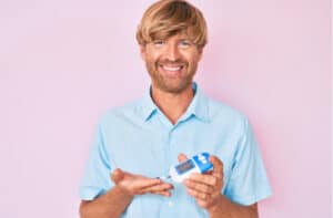 man using glucose meter smiling with a happy and cool smile on face.