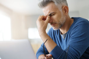 Man running in between his eyes as he suffers from an ocular migraine