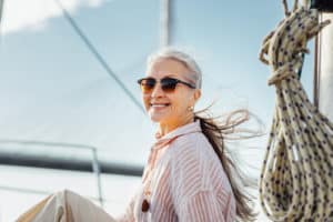 Portrait of a happy mature woman wearing sunglasses on a yacht.