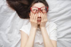 Woman laying down rubbing her eyes due to floaters in Chesapeake, VA