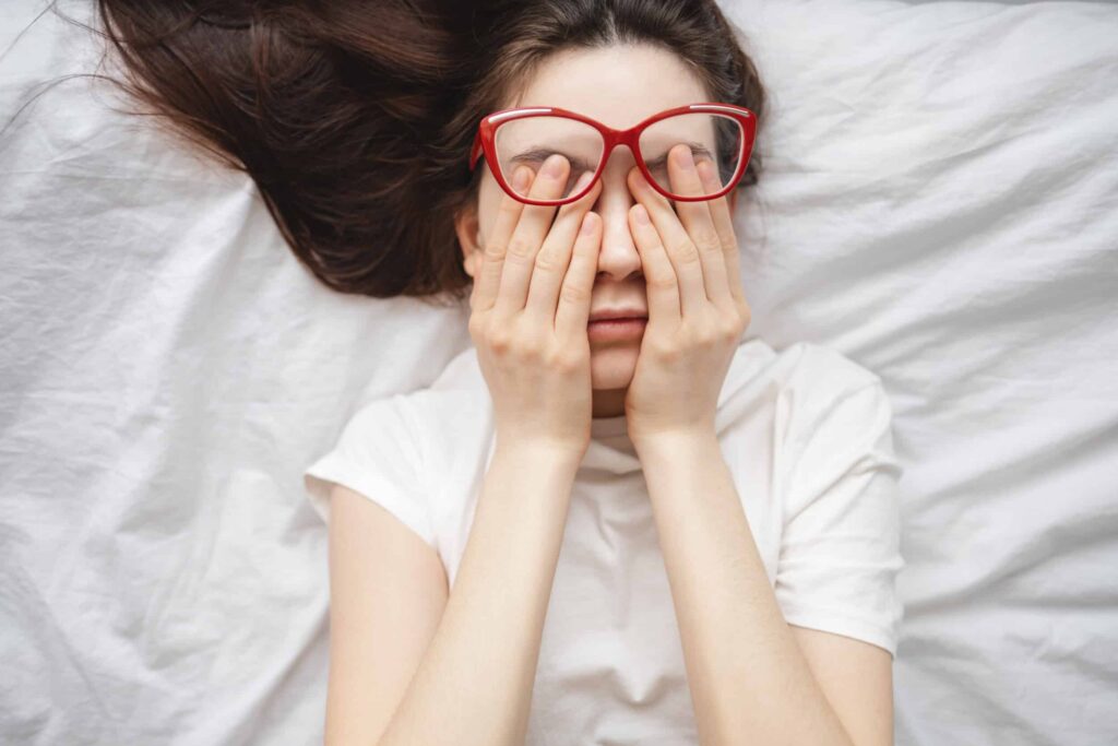 Are Eye Floaters Normal? What You Should Know 1 Woman laying down rubbing her eyes due to floaters in Chesapeake, VA