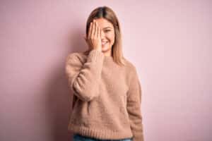 Woman smiling, covering one eye during eye exam for astigmatism in Chesapeake, VA