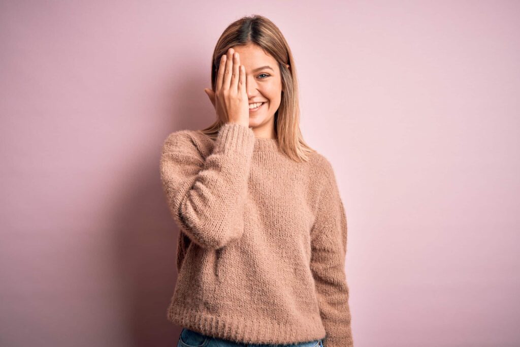 Woman smiling, covering one eye during eye exam for astigmatism in Chesapeake, VA