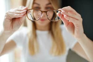 Woman taking off her eyeglasses, because she doesn't need them after iLASIK surgery in Chesapeake, VA