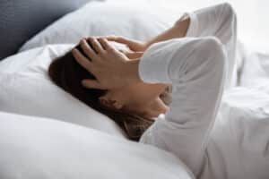 Woman in bed holding her head due to an ocular migraine in Chesapeake, VA
