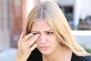 Woman touching her eye in discomfort due to eye floaters in Chesapeake, VA